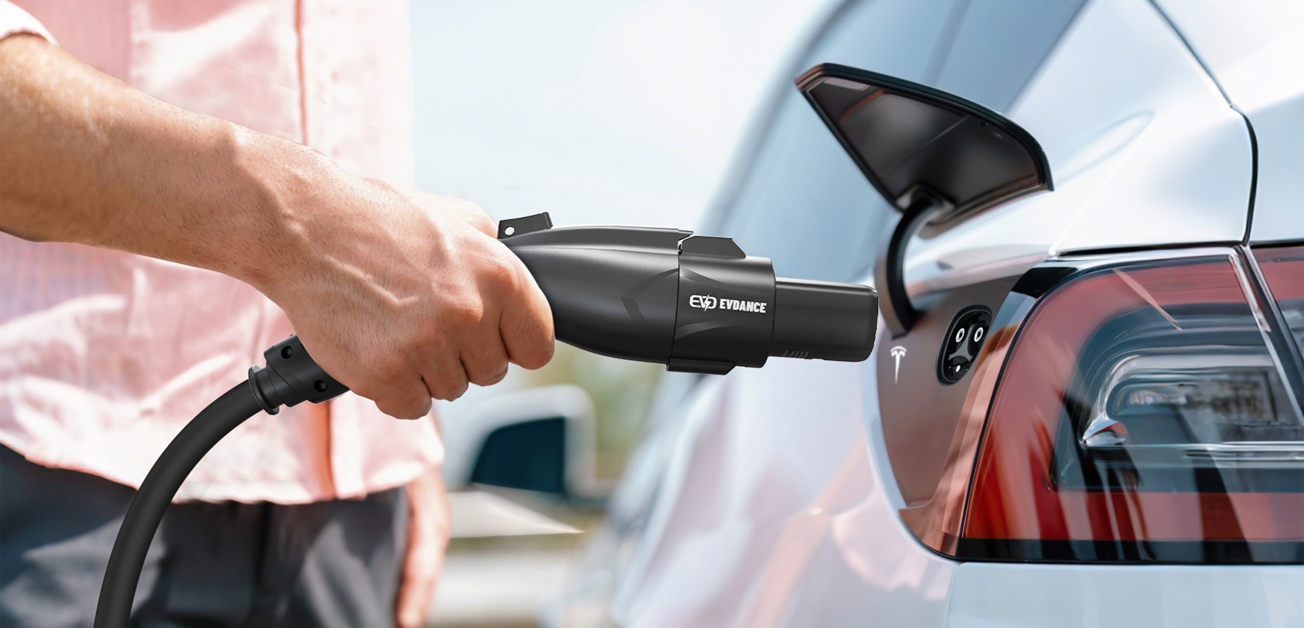 Close-up of a hand plugging an EVDANCE portable EV charger connector into a car